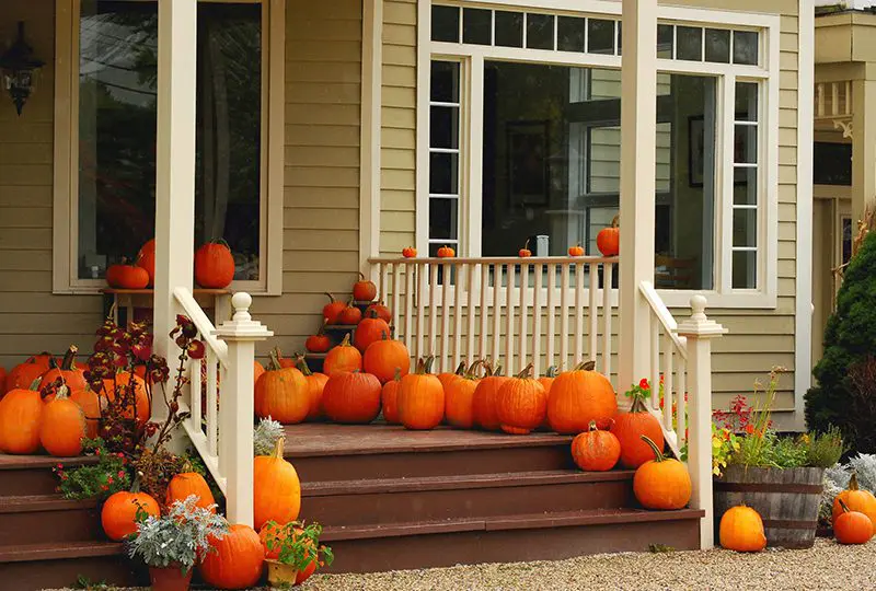 Pumpkins on porch steps of house.